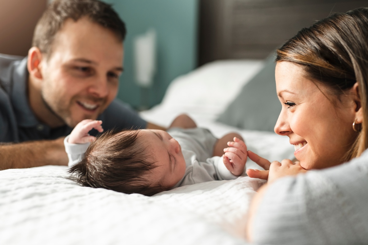 Financial strategies for new parents; a couple with newborn baby on a bed.