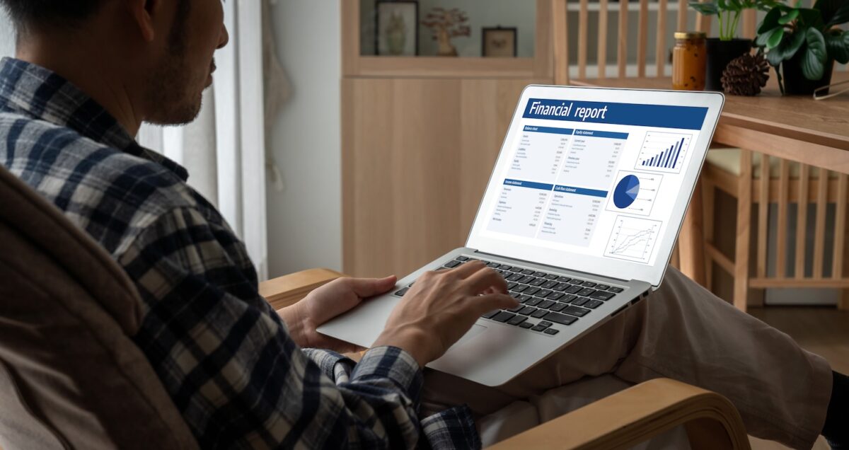 Man in a plaid shirt analyzing a financial report on his laptop, representing the decision between DIY investing and partnering with a financial advisor for strategic wealth management.